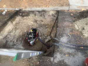 Pipe burst machine after being lowered into hole in homeowners yard. Pipe bursting is a method used by Inland Trenchless as part of its Trenchless no digging sewer repair.